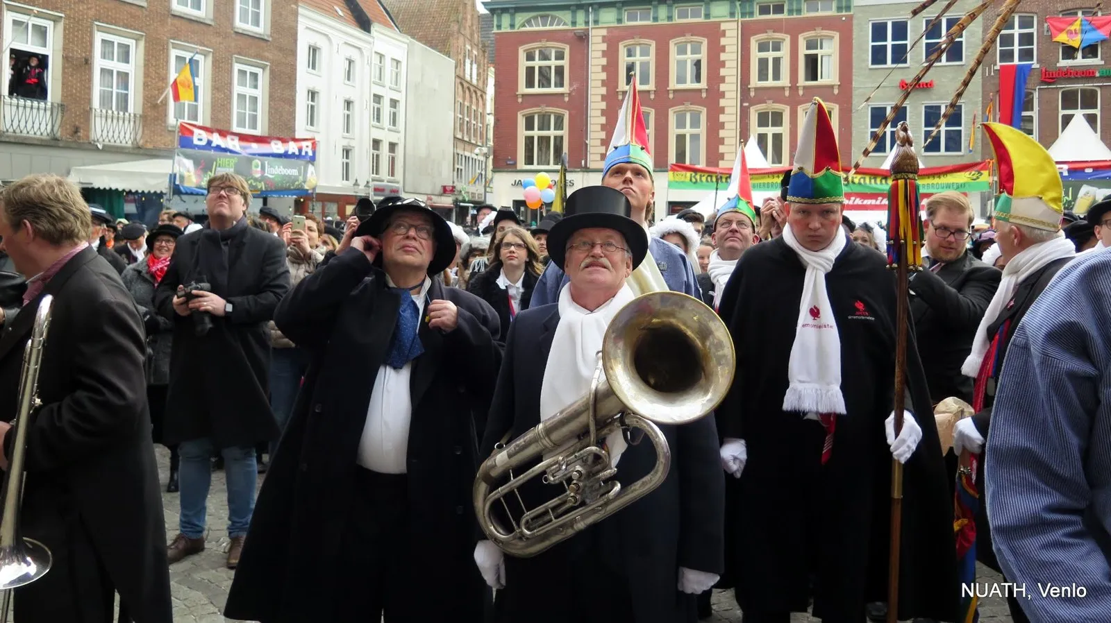 Muzikante van NUATH met tuba, in zwart pak met hoge hood.
